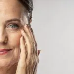 donna-matura-di-smiley-con-trucco-sulla-posa-con-la-mano-sul-viso.jpg